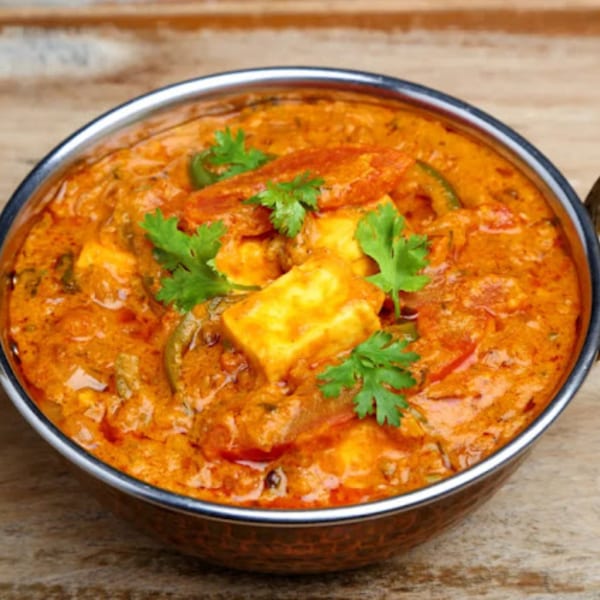 Sherpa Indian Kitchen's paneer butter masala, garnished with fresh cilantro, in a copper serving bowl.