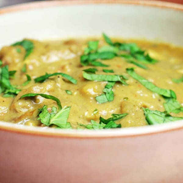 Close-up of a bowl of Sherpa Indian Kitchen's creamy green curry, garnished with fresh herbs.